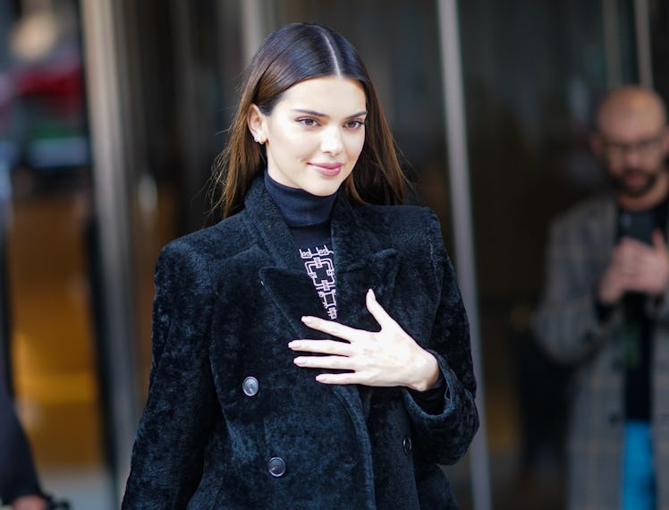 Ms. Kendall Jenner in a black jacket, standing outside.