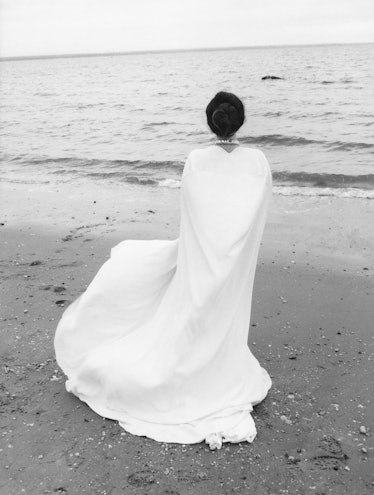 Lana del Rey back turned on the beach covered in Valentino gown wearing a Swarovski necklace.