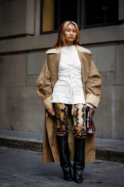 A guest wearing white top, brown coat, and black leather boots 