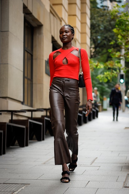 Malaan Ajang wearing a red cut-out knit top and dark brown leather pants 