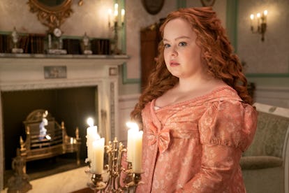 Nicola Coughlin as Penelope Featherington wearing a pink gown in front of candles and a fireplace