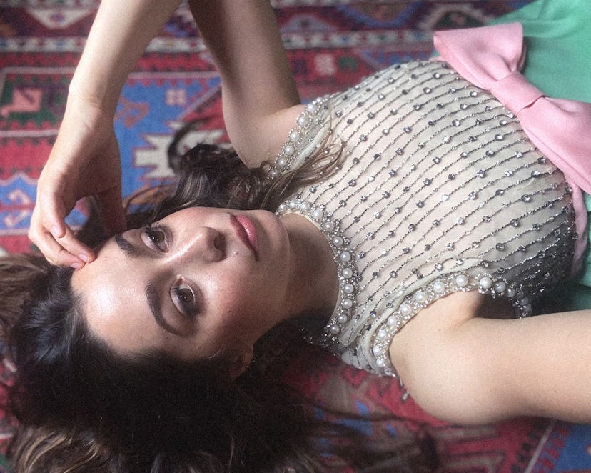 Cristin laying on the floor in a dress with her hand to her forehead