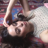 Cristin laying on the floor in a dress with her hand to her forehead
