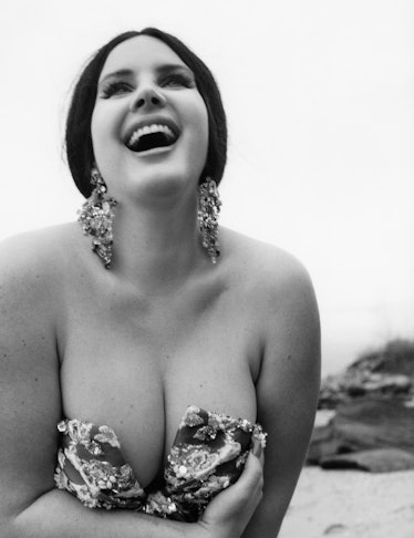 Lana del Rey smiling on the beach wearing a Valentino Haute Couture dress and Swarovski ear cuffs.