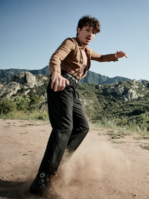 The actor sliding through sand and brings the dust up in a shirt, pants and shoes by Saint Laurent a...