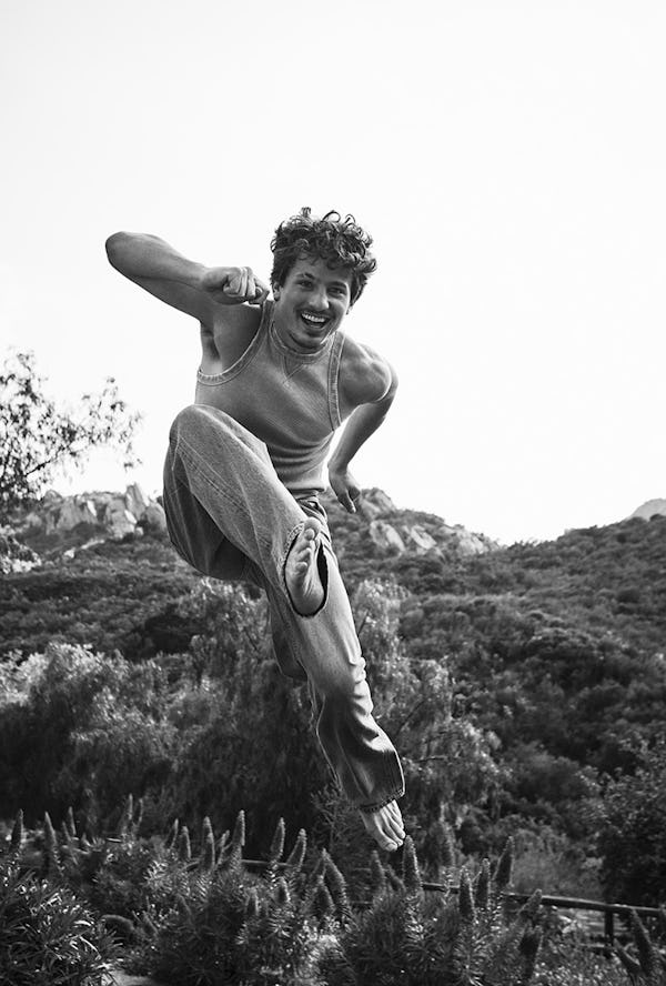 Black and white photo of Charlie Puth in a EYTYS tank and jeans jumping around in a field