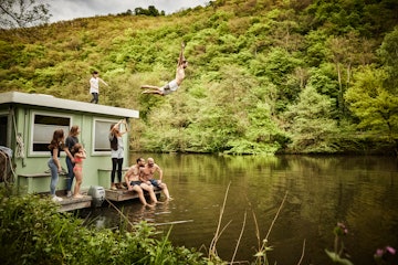 France as the epic family adventure vacation location - a man jumping into the lake from the roof of...