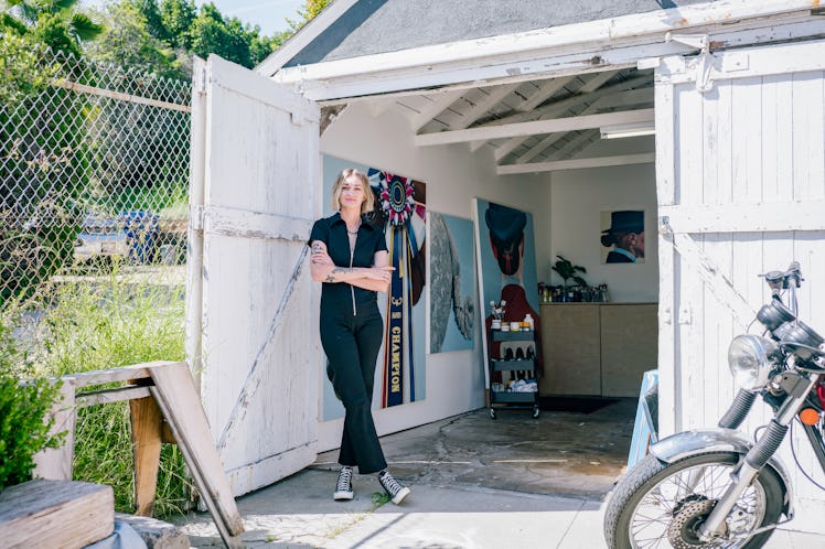 Sarah Miska wearing a black jumpsuit, standing in front of the open doors of her studio in Los Angel...