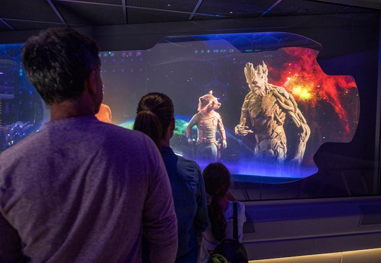 A group of people watching a screen with Groot from 'Guardians of the Galaxy'