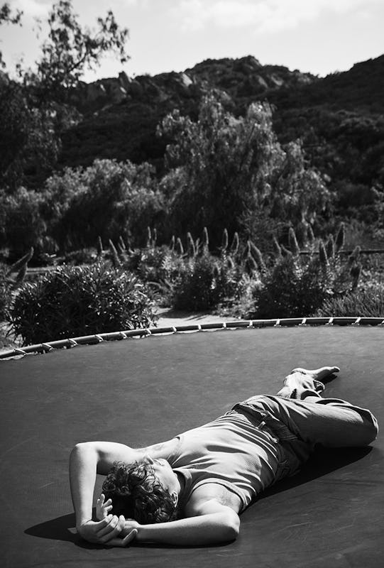 Black and white photo of Charlie Puth in a EYTYS tank and jeans laying on a trampoline