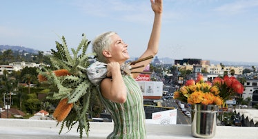 Michelle Williams carrying a bouquet of flowers with her arms up