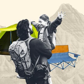 A dad in hiking gear carries his daughter while there is a tent a camping chair and a mountain in fr...