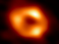 bright orange circle on a dark background with a dark region in the middle. 