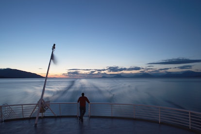Alaska as the epic family adventure vacation location - a man looking at the sea and the sunset