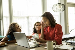 Stressed mother working from home with children in background