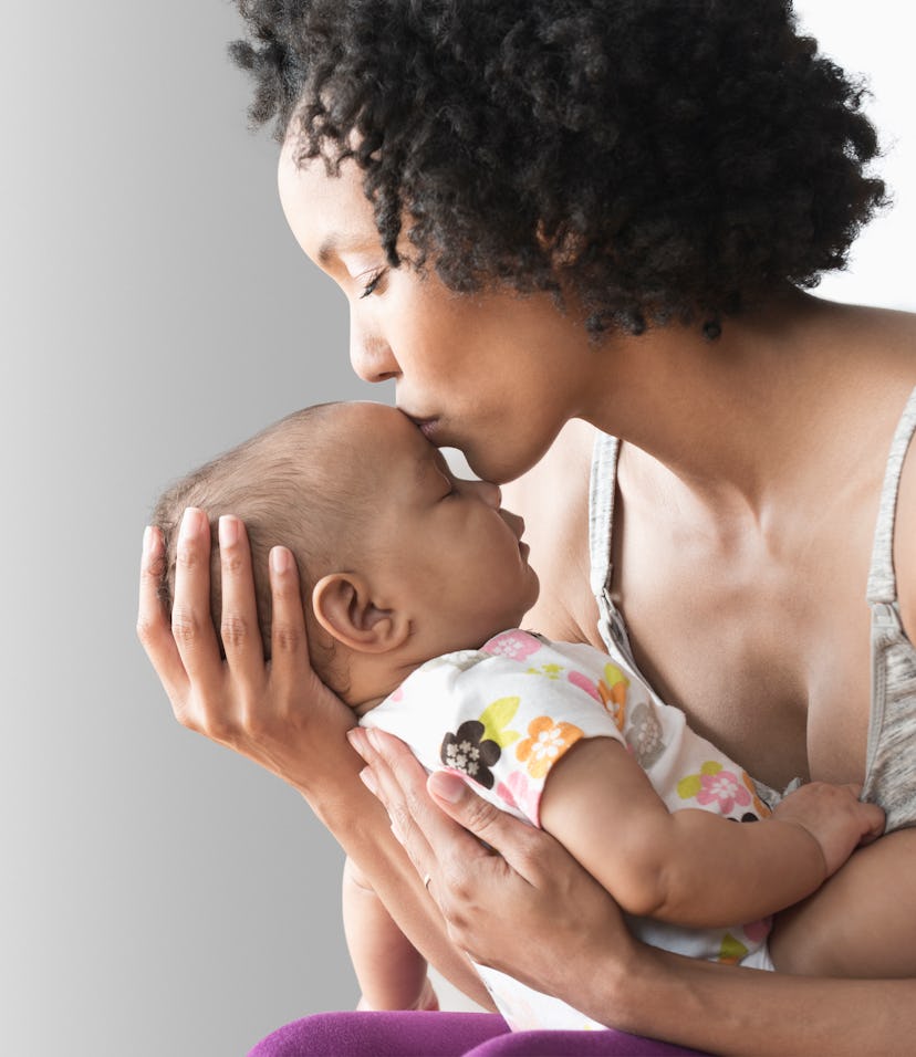 woman holding newborn and kissing baby's head can relate to these new mom quotes