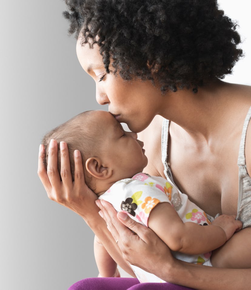 woman holding newborn and kissing baby's head can relate to these new mom quotes 