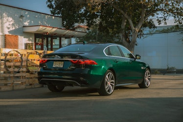 Green Jaguar XF parked next to a tree