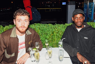 musicians Bazzi and ASAP Nast sitting at a restaurant table outdoors
