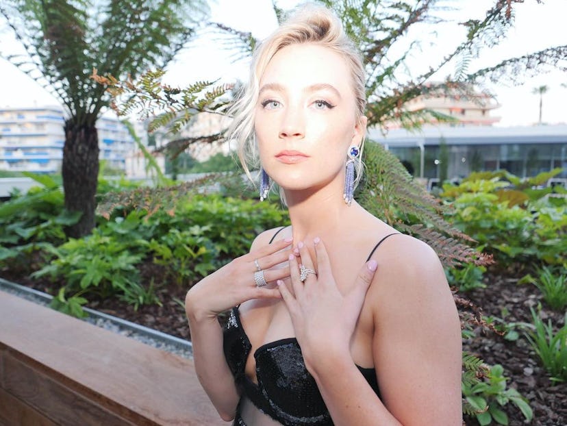 Saoirse Ronan wearing a black bra and sapphire and diamond earrings