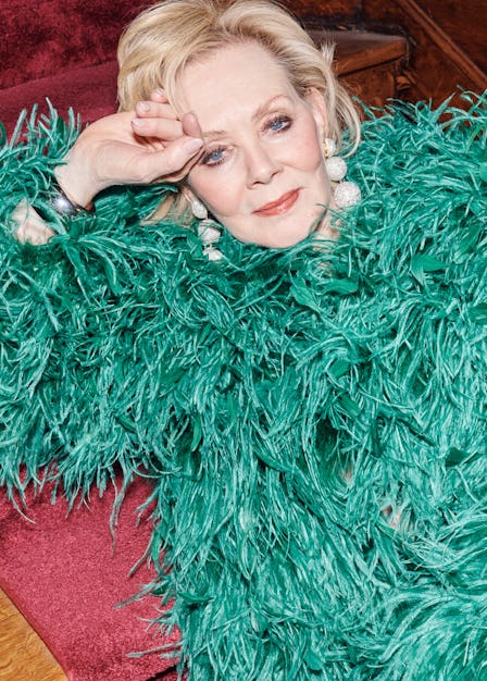 Jean Smart in a green feathered Valentino coat and Rebecca De Ravenel earrings, lounging on the red ...