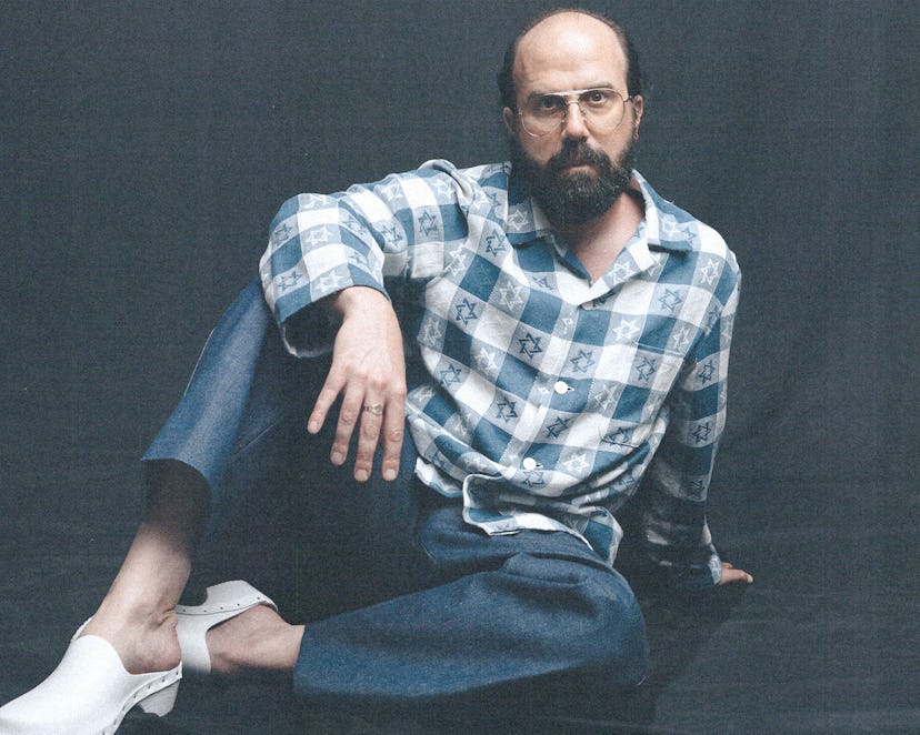 Brett Gelman wearing a blue and white checkered button down with stars of David all over it, jeans, ...