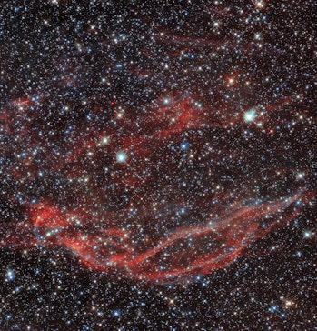 Red filaments at the bottom of this image curve upwards. Two bright stars near the center of the ima...