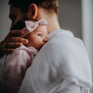 A new dad with postpartum depression holding his newborn daughter.