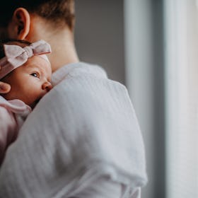 A new dad with postpartum depression holding his newborn daughter.