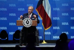 Greg Abbott speaking at the NRA forum with the Texas flag behind him