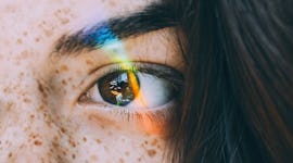 a woman looking into a rainbow with a clear skin after using one of the best korean skincare product...