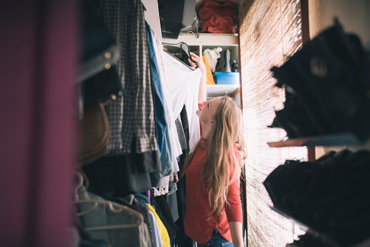 Young woman standing in her closet after moving into her first apartment.
