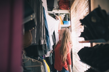 Young woman standing in her closet after moving into her first apartment.