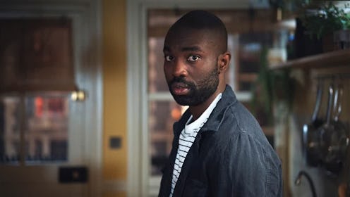 Papp Essiedu as George in the Lazarus Project, warily looks to camera wearing a blue/grey jacket and...