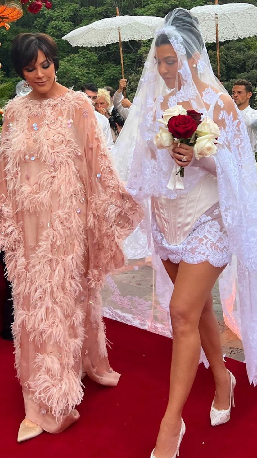 Kourtney Kardashian in a wedding dress walking with her mother Kris Jenner