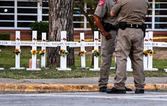 Police officers stand near a makeshift memorial for the shooting victims at Robb Elementary School i...