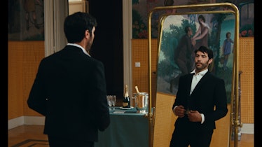Tahar Rahim as Laurent, staring at himself in a mirror while wearing a suit