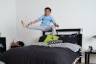 一个小孩在床上跳来跳去踢来踢去，穿着睡衣盖着他的忍者夜服……