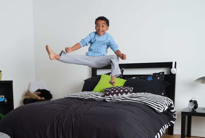 A kid jumping on the bed and doing kicks while wearing his pajamas over his Ninjamas Nighttime Under...