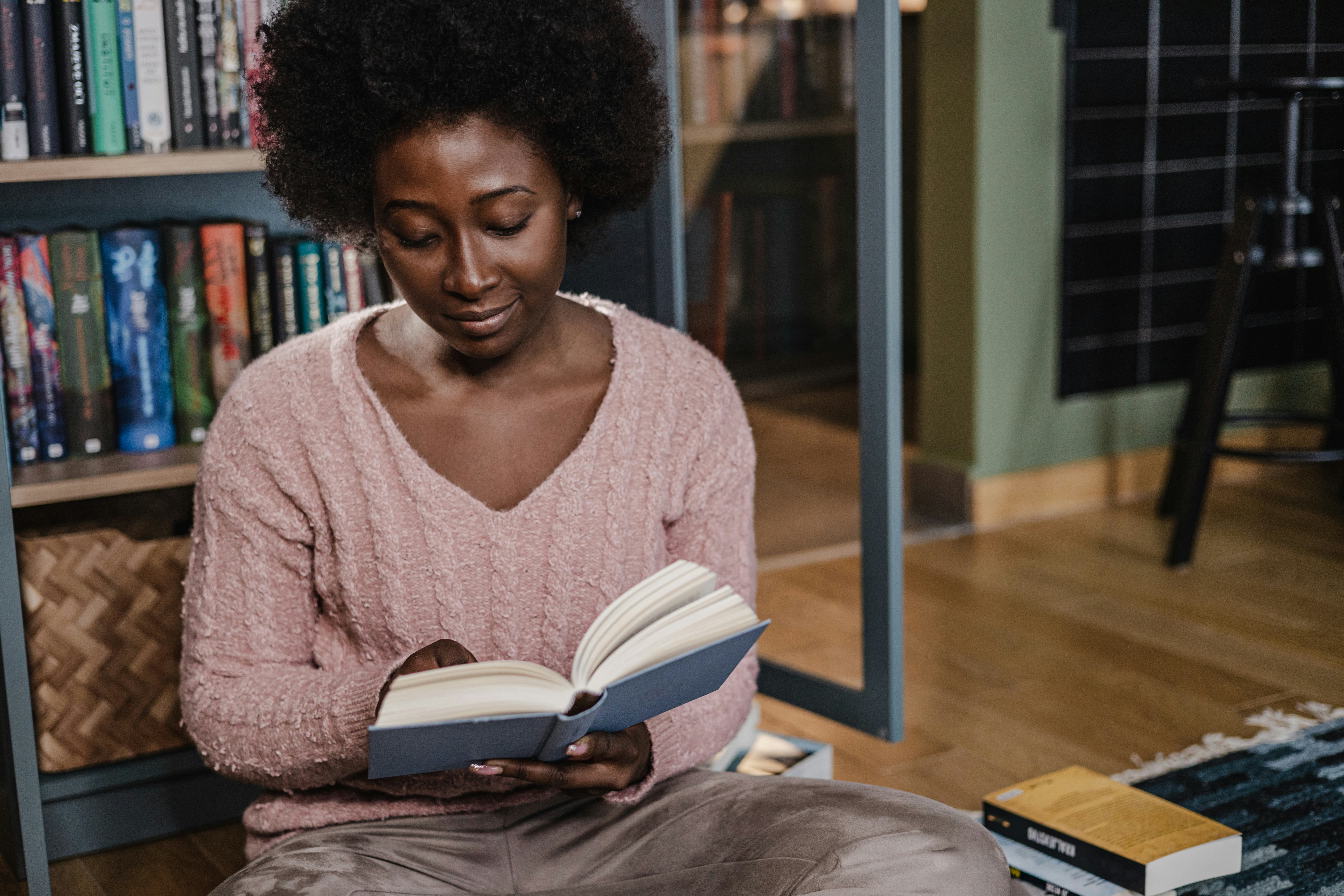 A young woman reading a book on the floor and concentrating.