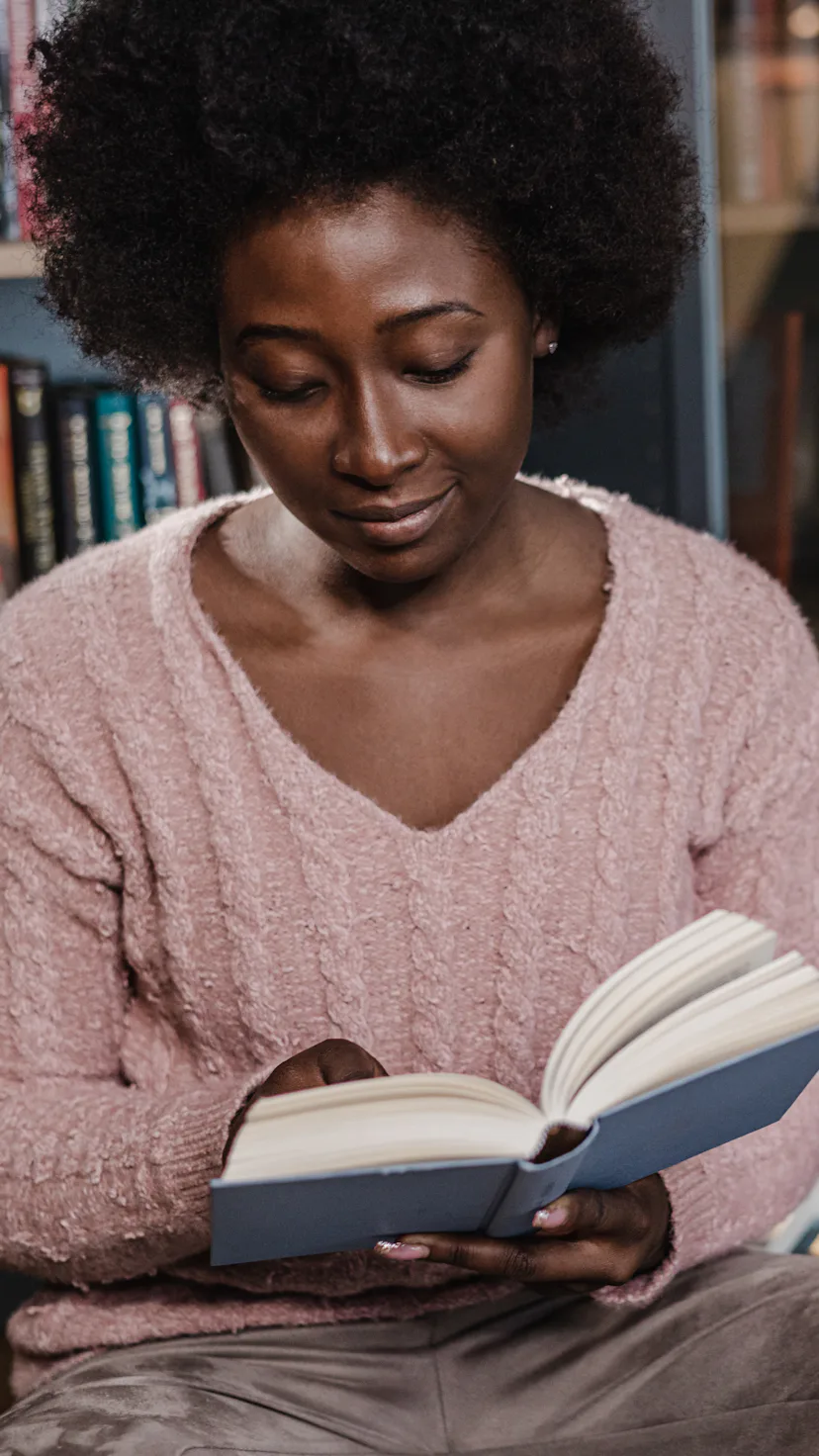 A young woman reading a book on the floor and concentrating.