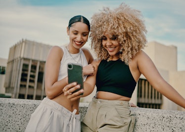 Two young women taking a selfie after reading their June 2022 horoscope.