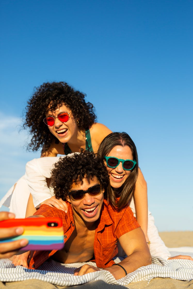 Three young friends taking a selfie on the beach on June 4, 2022, the best day of the month for ever...