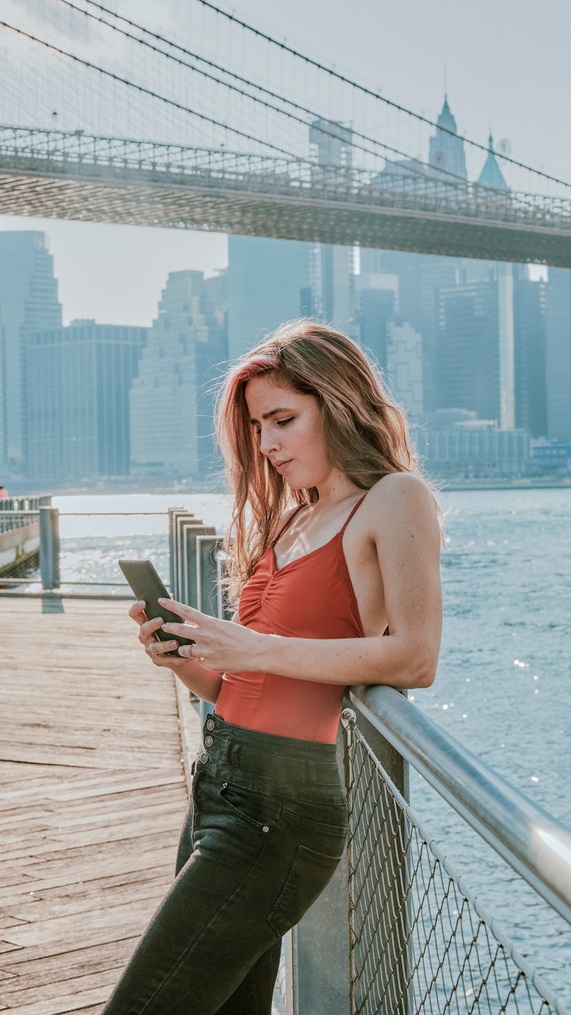 Young woman texting by a bridge on June 3, when Mercury retrograde spring 2022 ended.