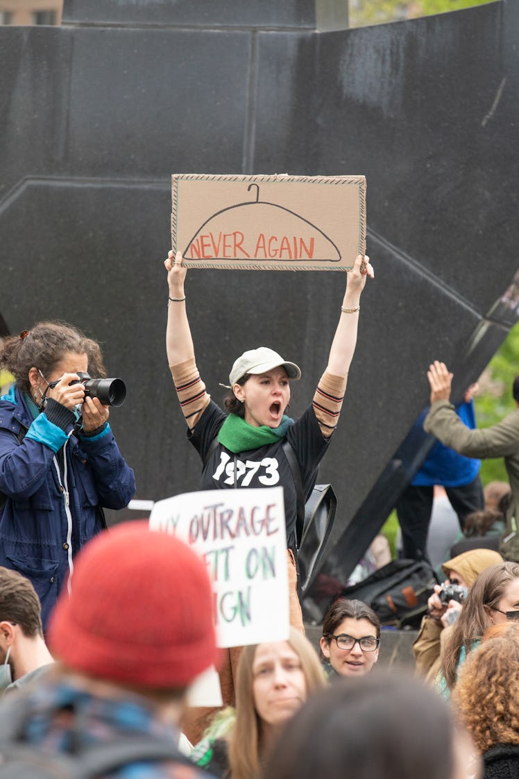 A protester holding up a pro-choice sign with a coat hanger that reads "never again"