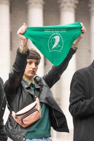 A person holding up a green bandana in support of abortion rights