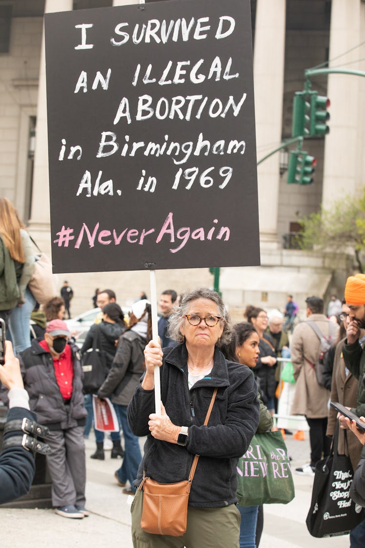 A person holding up a sign that reads "I survived an illegal abortion in Birmingham Ala. in 1969 #Ne...