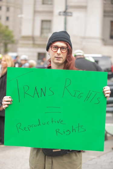 A person holding up a sign that reads "trans rights = reproductive rights