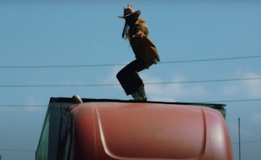 Orville Peck pictured in the Daytona Sand video standing on top of an 18-wheeler