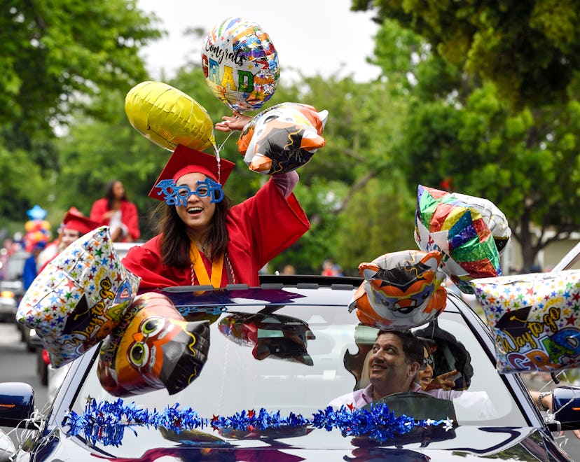 Los Alamitos High School graduate in a car with graduation-themed decorations